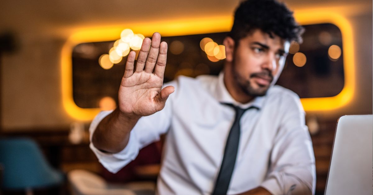 Man holding up hand to the camera indicating disinterest