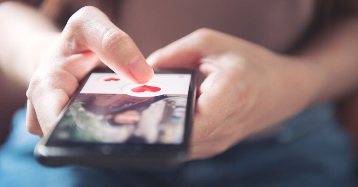 Online dating expectations | Hands holding a phone and pressing a heart on a dating app