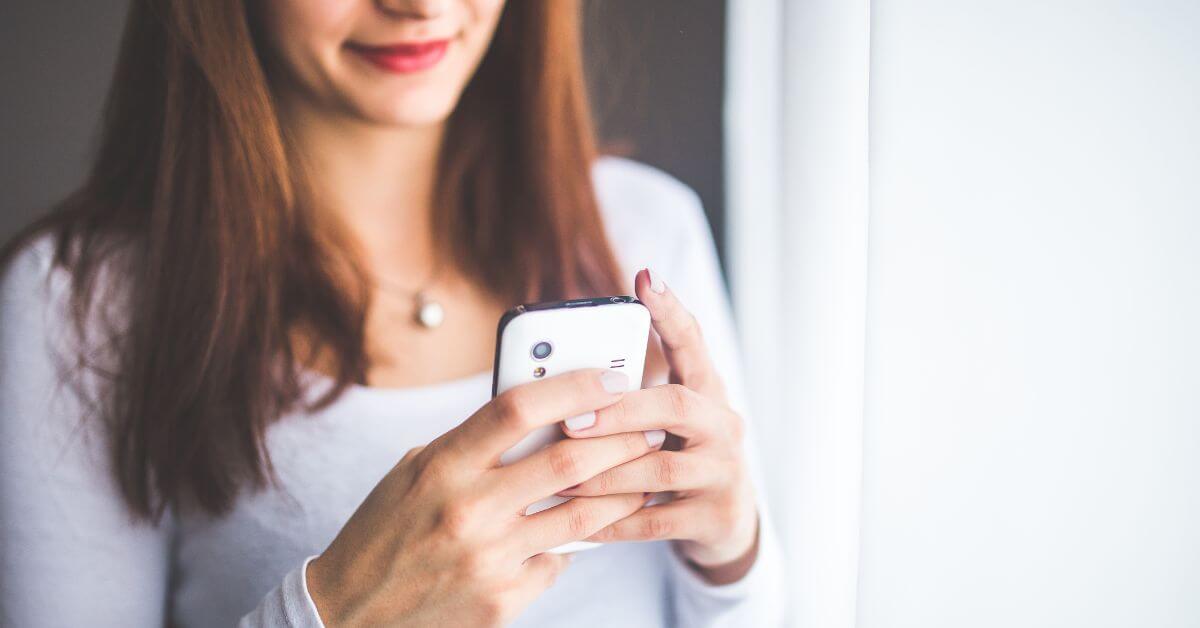 messages to grab her attention | woman holding a phone a smiling